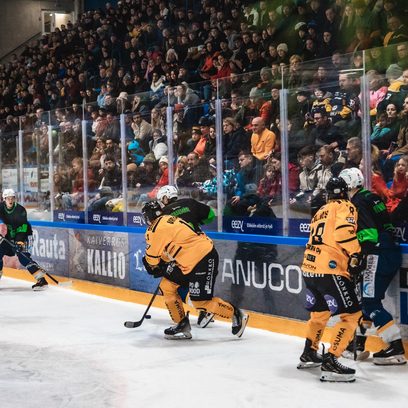 Hockey game in progress with players on the ice and spectators in the stands.