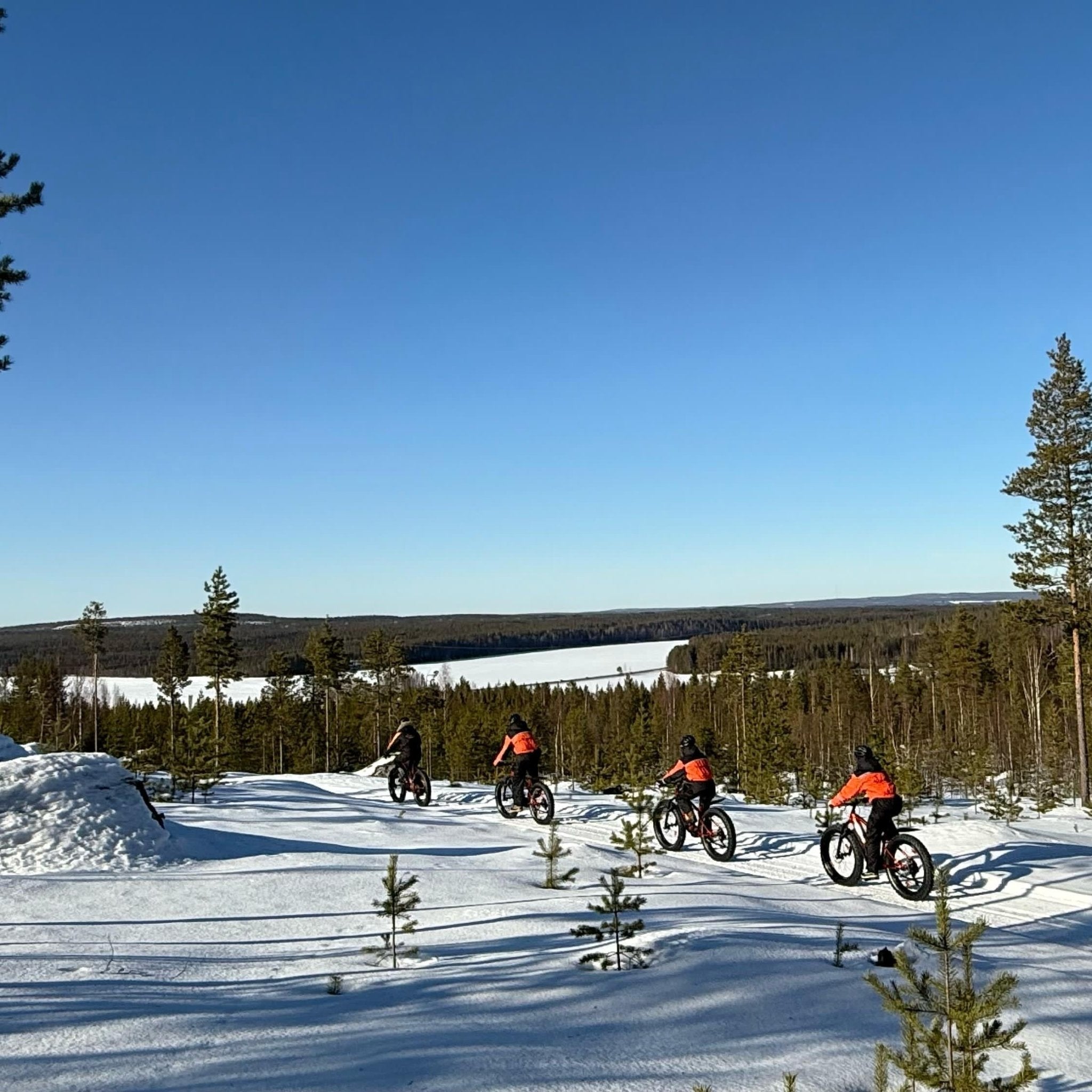 Electric Fat Bike Adventure at a Reindeer Farm on snowy Arctic trails with riders in orange jackets Porovaara
