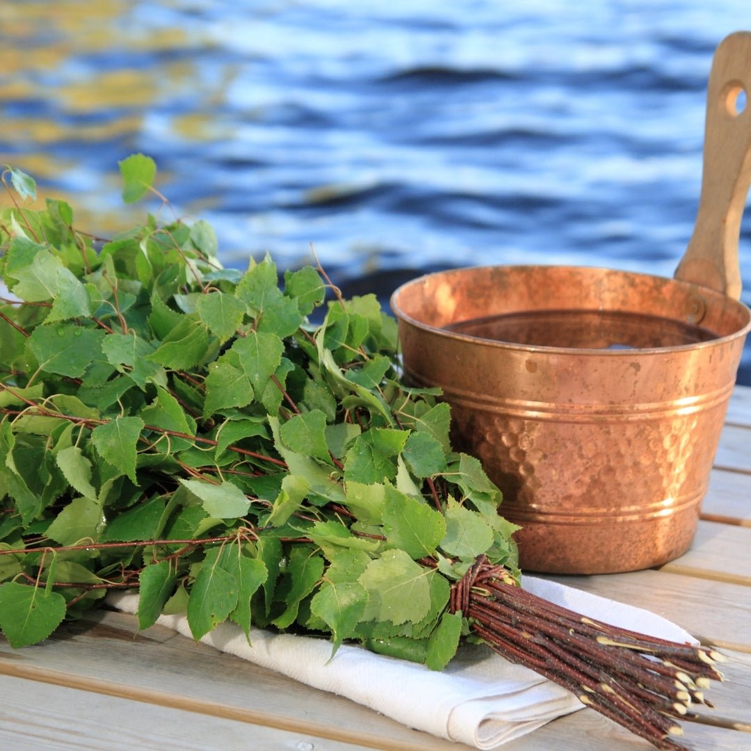Traditional sauna birch whisk and water bucket by lake shore for Experience summer finnish sauna and lake by Lapin Väki