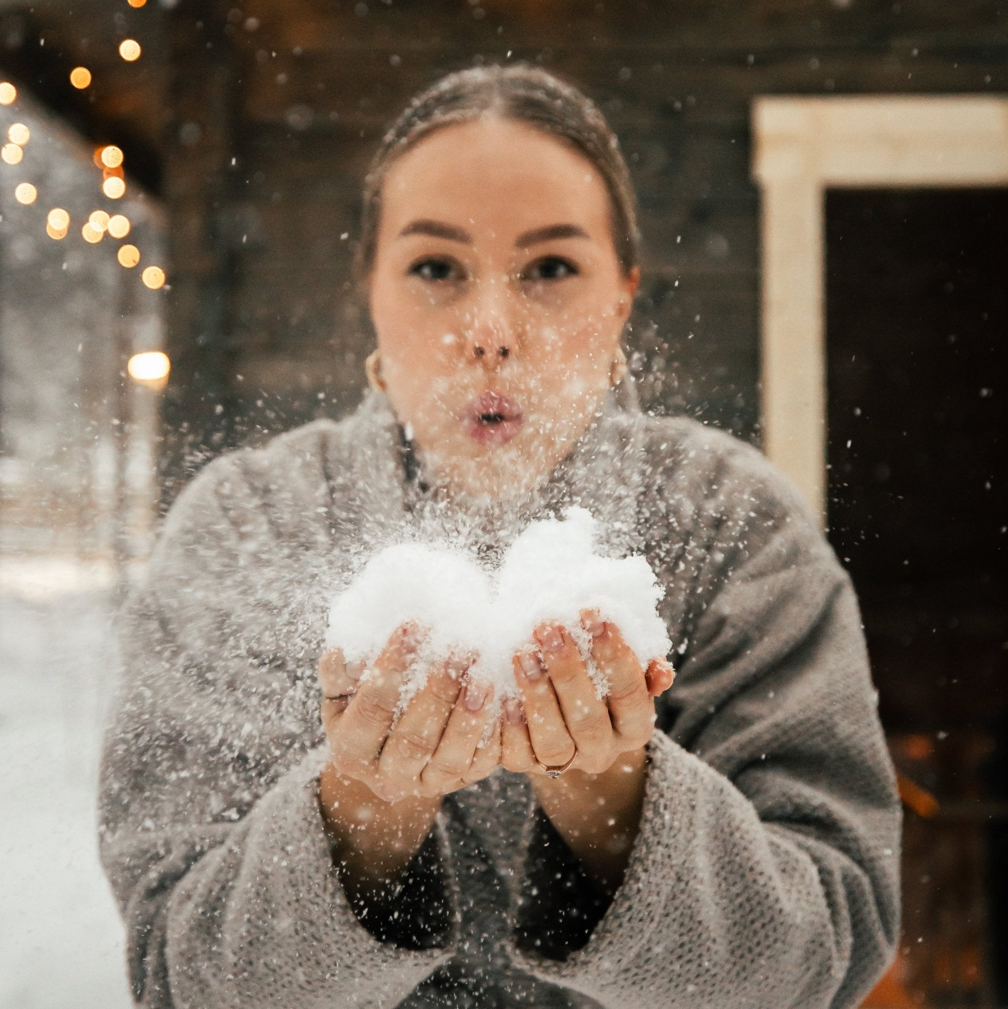 Woman blowing snowflakes in a snowy outdoor setting