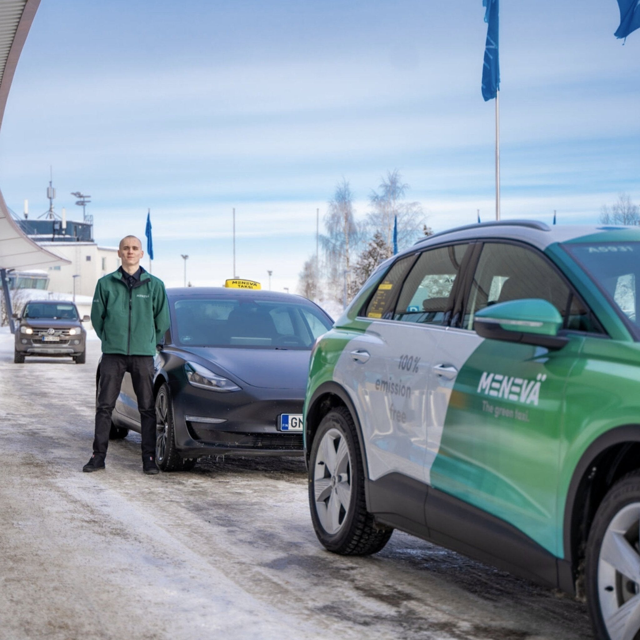 Person standing next to a green and white car at a snowy location
