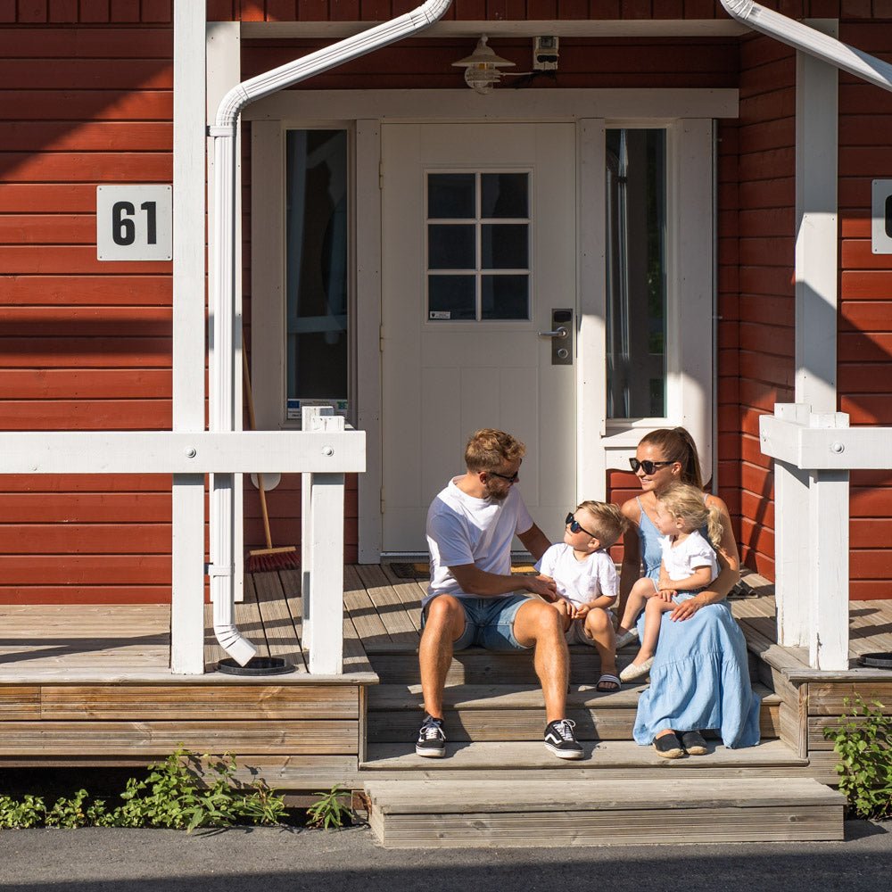Family relaxing on porch of red cottage in Santa Claus Holiday Village with modern amenities Santa Claus Holiday Village