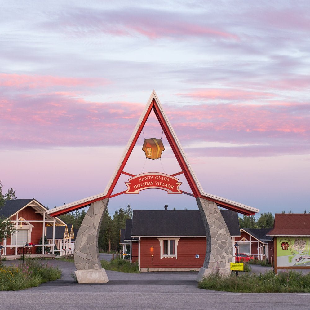 Entrance arch to Santa Claus Holiday Village with cottages and colorful sunset sky Santa Claus Holiday Village Santa Claus Holiday Village