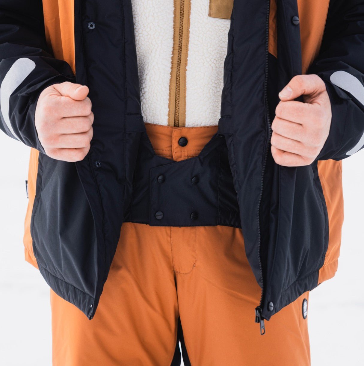 Close-up of a person wearing Winter Clothing Set Rovaniemi in orange and black by WinterRent