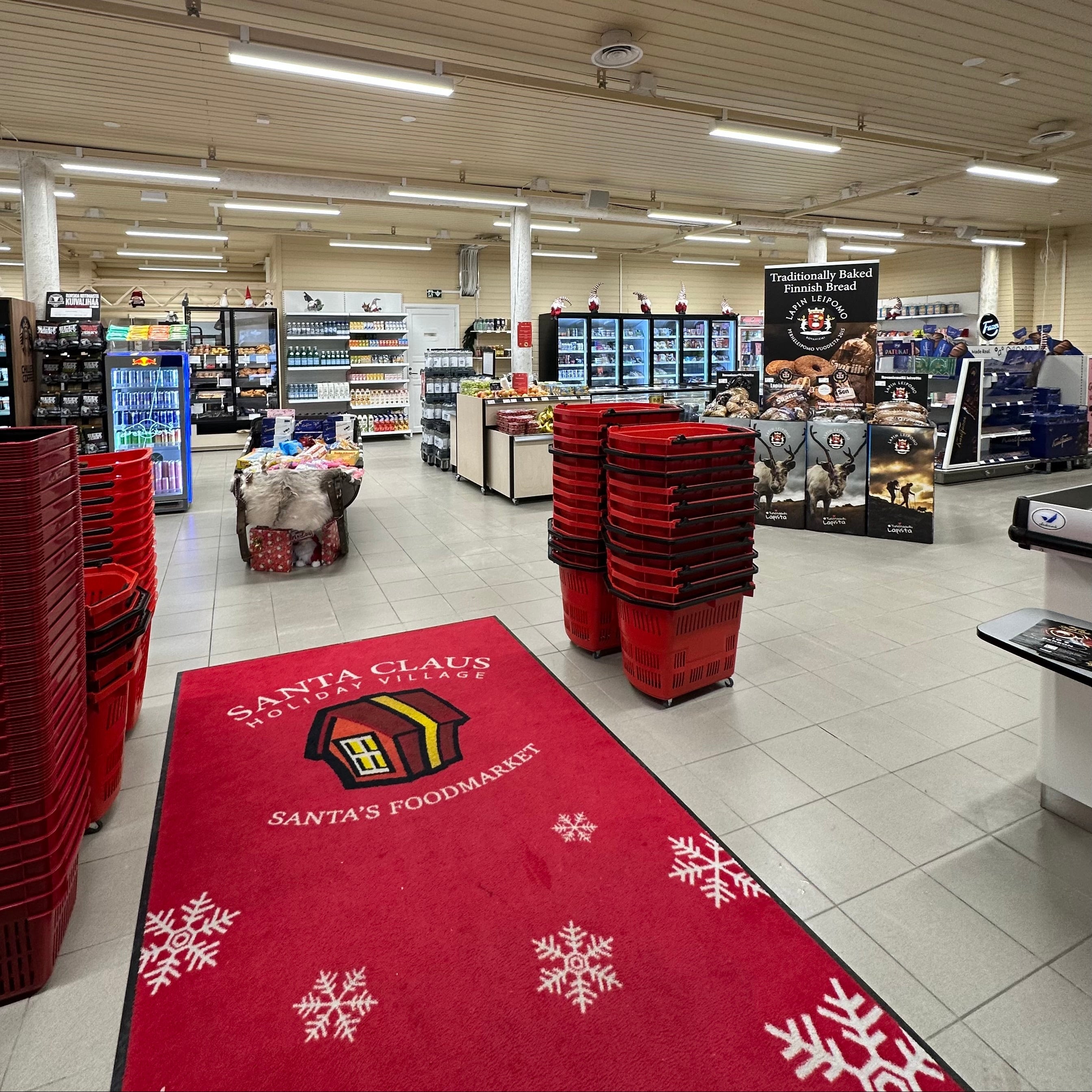 Supermarket interior with a red mat featuring 'Santa's Foodmart' branding.