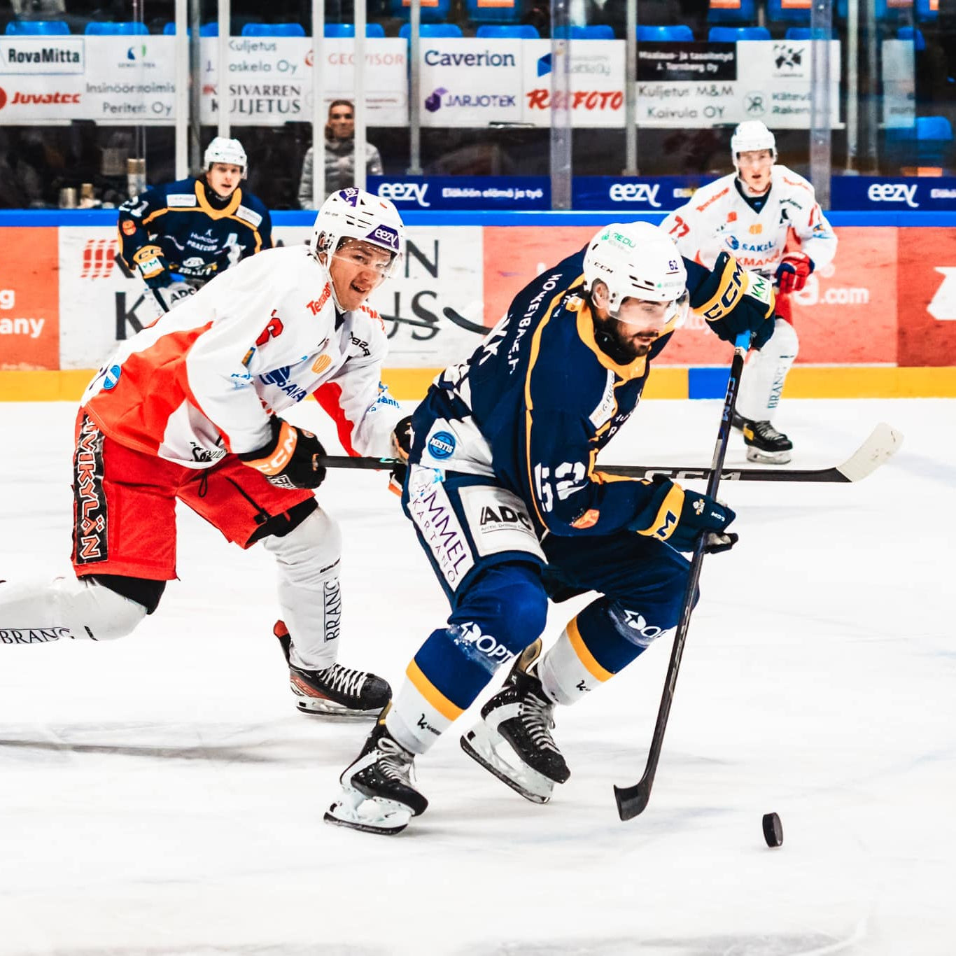 Hockey game in progress with players on the ice, surrounded by advertisements.