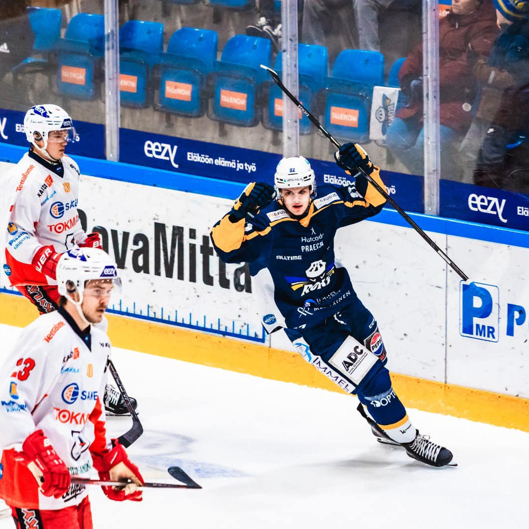 Hockey player in action on the ice with teammates and opponents in the background.