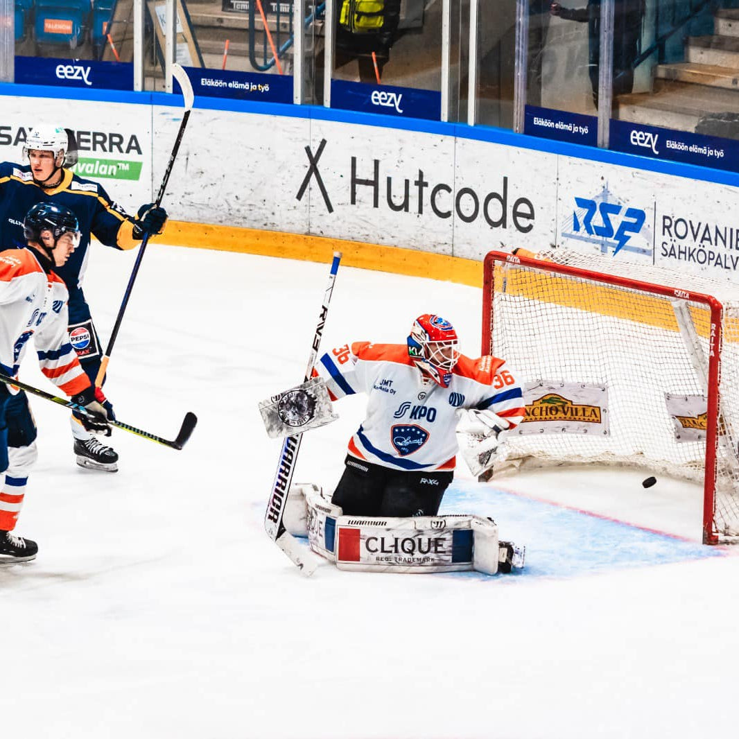 Hockey game in progress with players on the ice and a goal in the background.