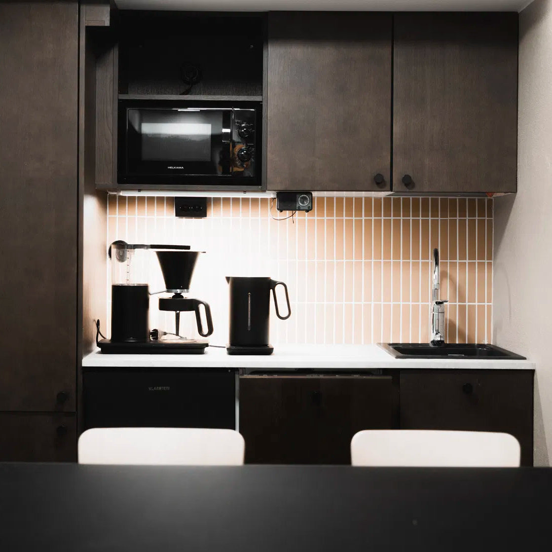 Modern kitchen with black appliances and white cabinets.