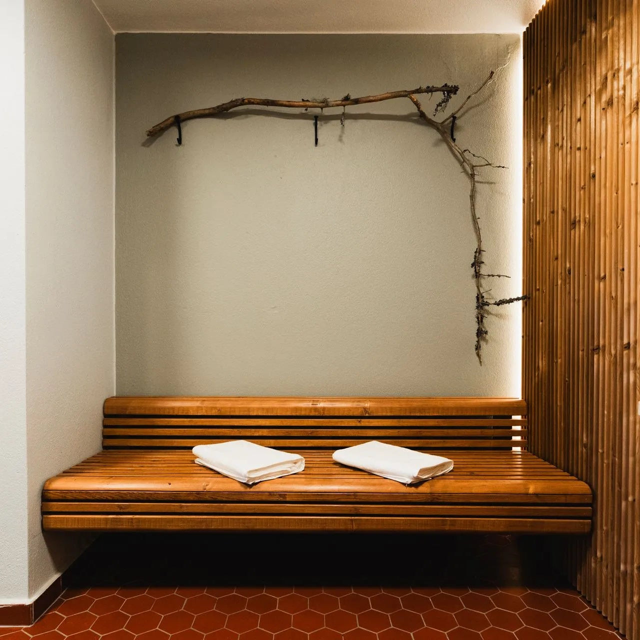 Wooden bench with towels in a room with wooden walls and a branch decoration.