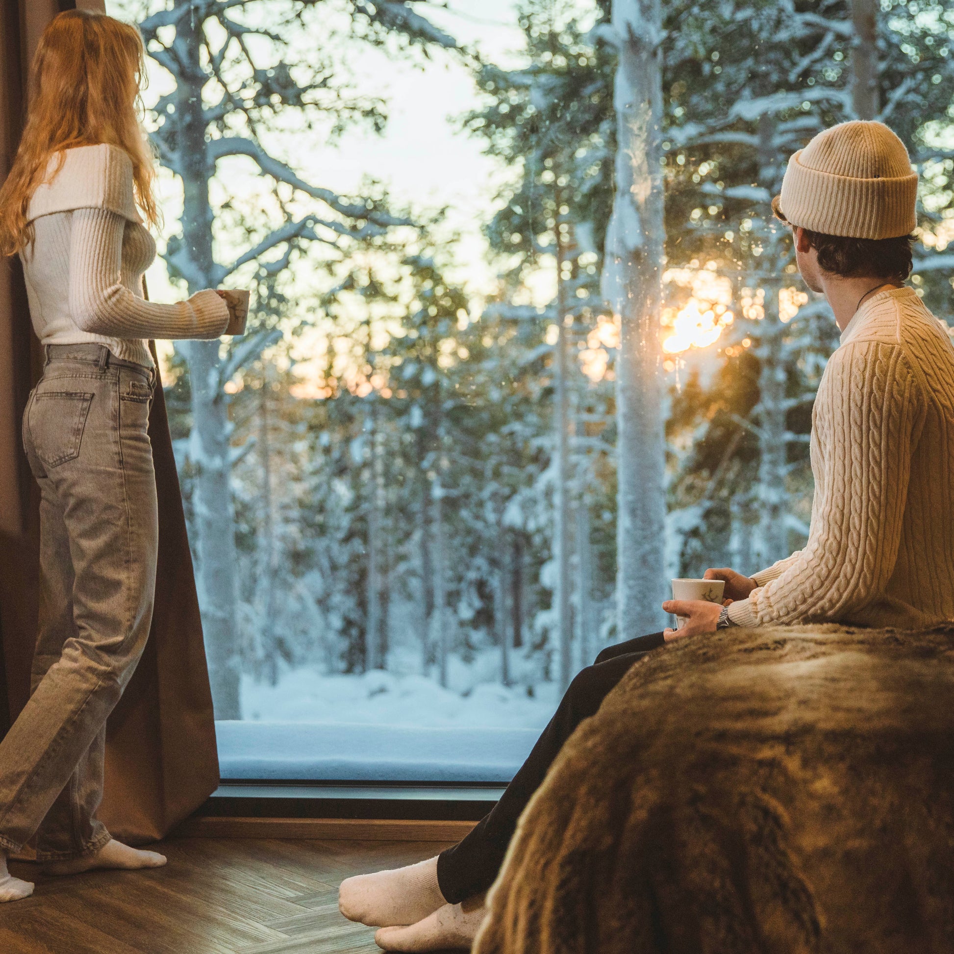 Couple enjoying snowy Arctic forest view from cozy cottage window in Lapland Most unique sleeping experience in Lapland Your City Guide