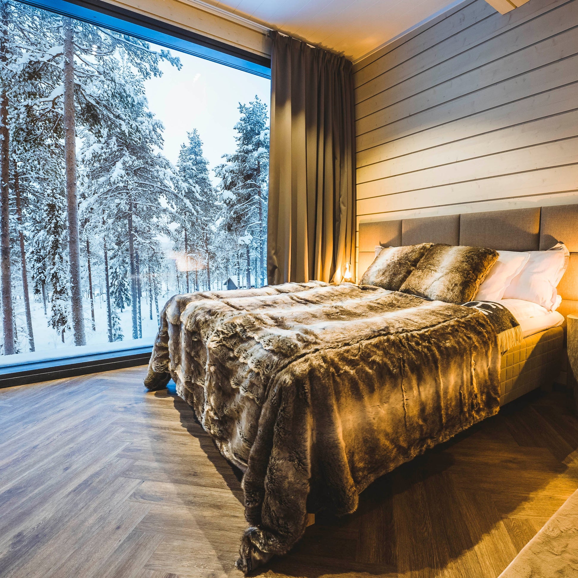 Cozy bedroom with fur blankets and large window showing snowy Arctic forest, Most unique sleeping experience in Lapland Your City Guide