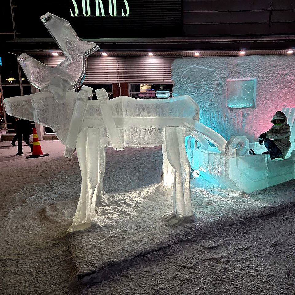 Ice sculpture of a dog and airplane with 'Sukus' branding in the background.