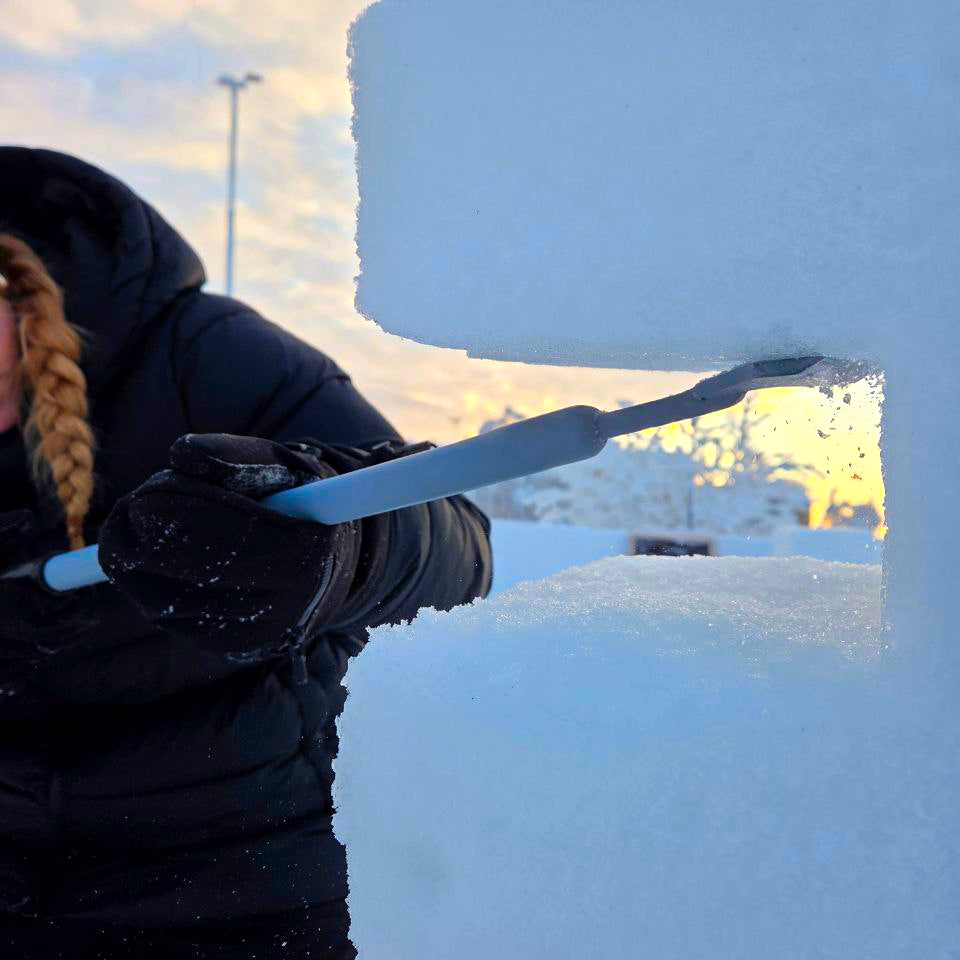 Person using a snow shovel to clear snow in a winter setting