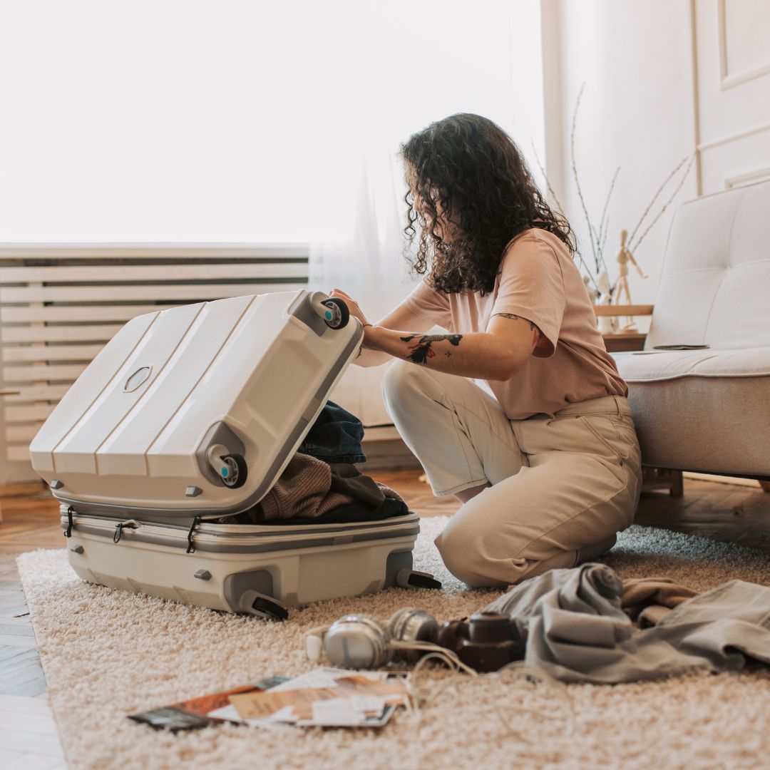 Person packing a suitcase in a living room with packing list