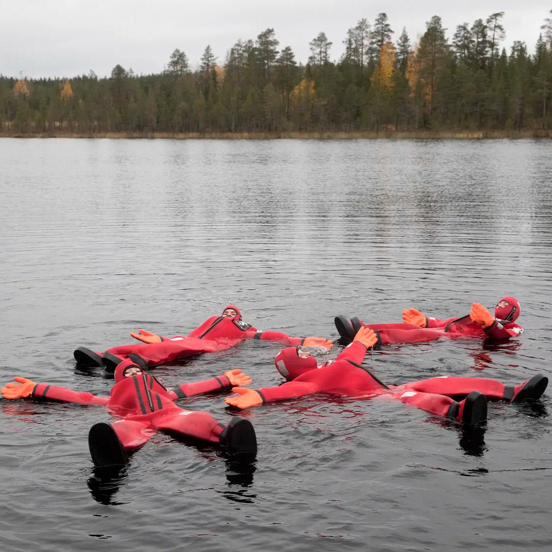 Four people floating in icy water wearing full-body rescue suits during Arctic floating in the wilderness Safartica