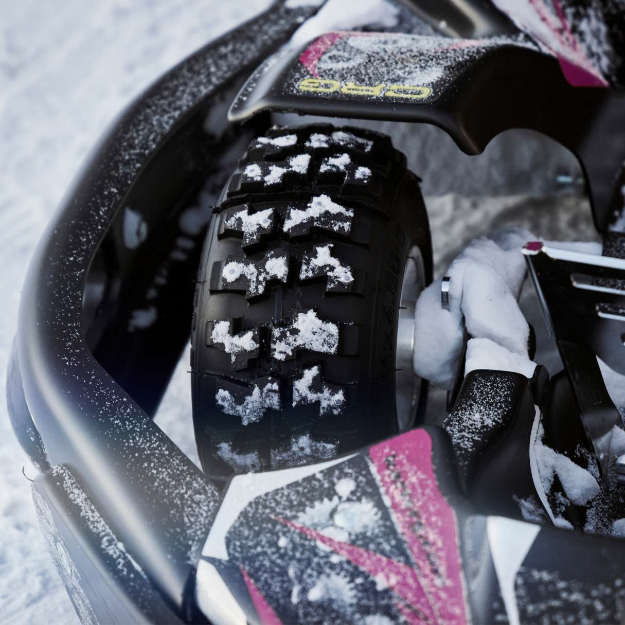 Close-up of a snowmobile tire with snow on a snowy ground