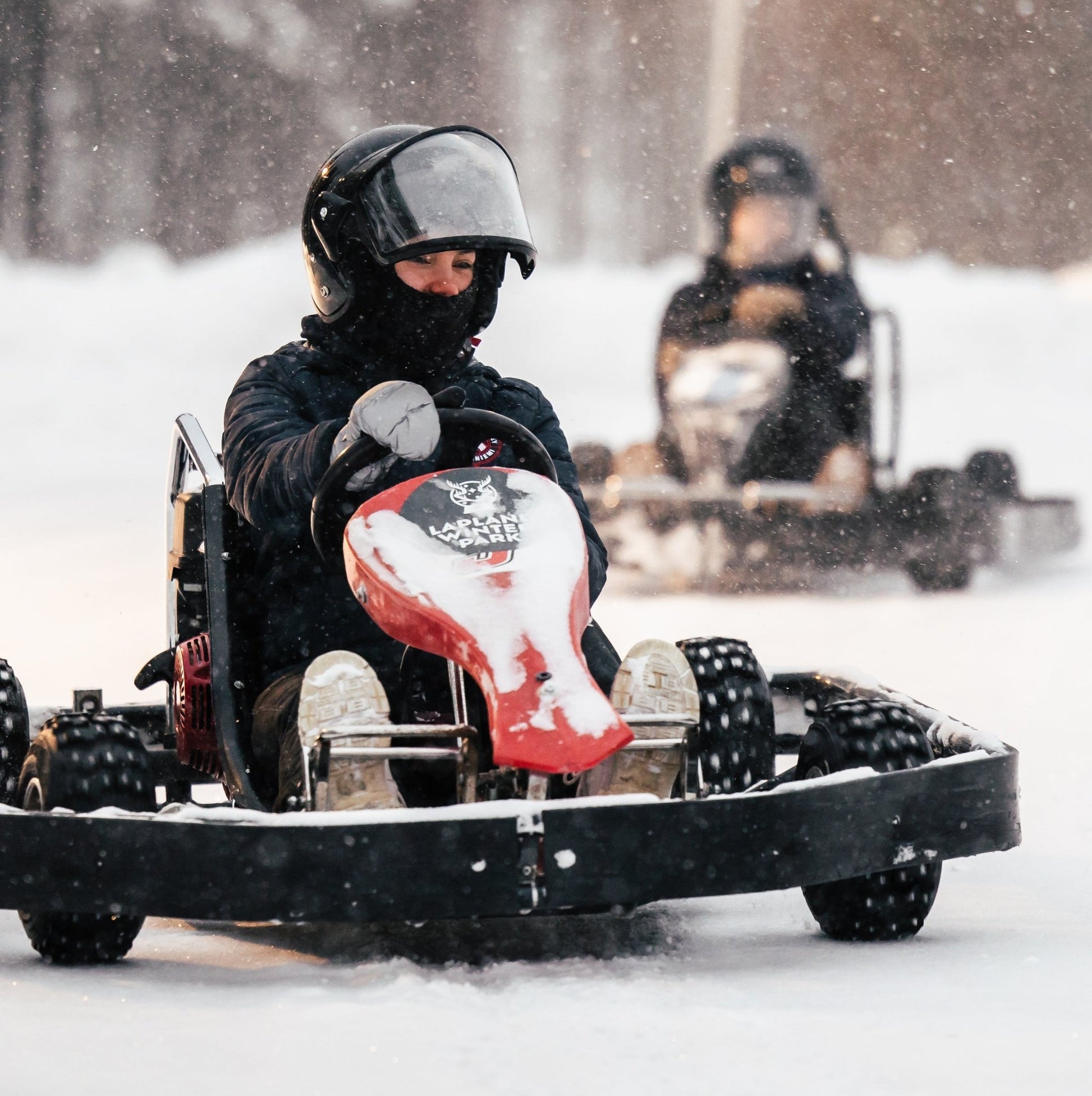 Two people riding ice karting on a snowy surface