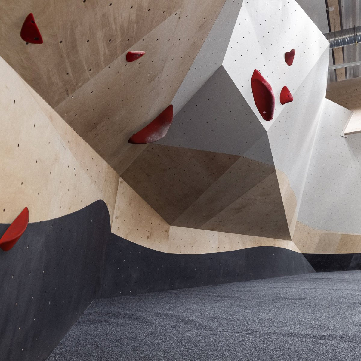 Indoor climbing wall with red holds for guided climbing experience at Lapin Väki, Rovaniemi's climbing gym.