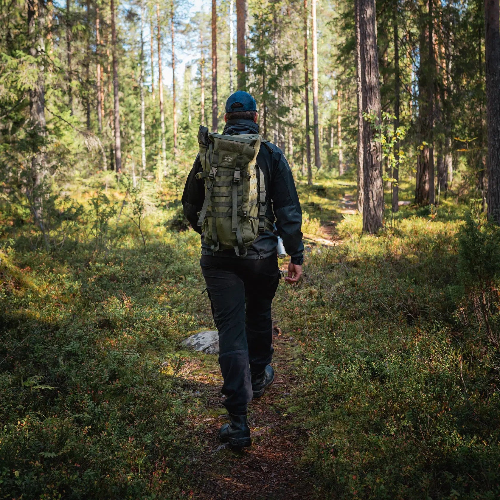 Person with backpack hiking through dense Finnish forest trail Magical Forest Hiking Adventure in Finnish forest Pure Lapland