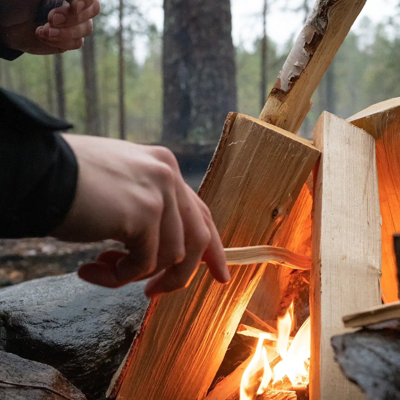 Hands starting a fire in Finnish forest during Magical Forest Hiking Adventure by Pure Lapland