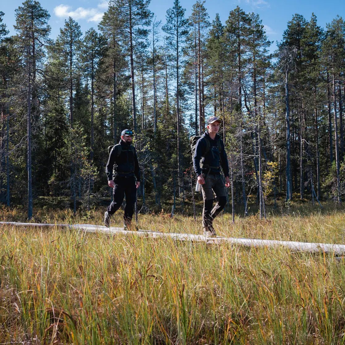 Two hikers walking on a trail in a Finnish forest during the Magical Forest Hiking Adventure by Pure Lapland