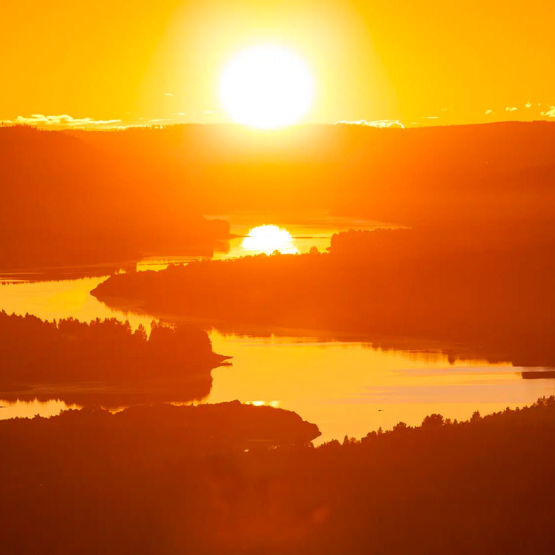 Bright midnight sun over a calm river and hills in Lapland for Midnight Adventure with Quad Bikes Pure Lapland