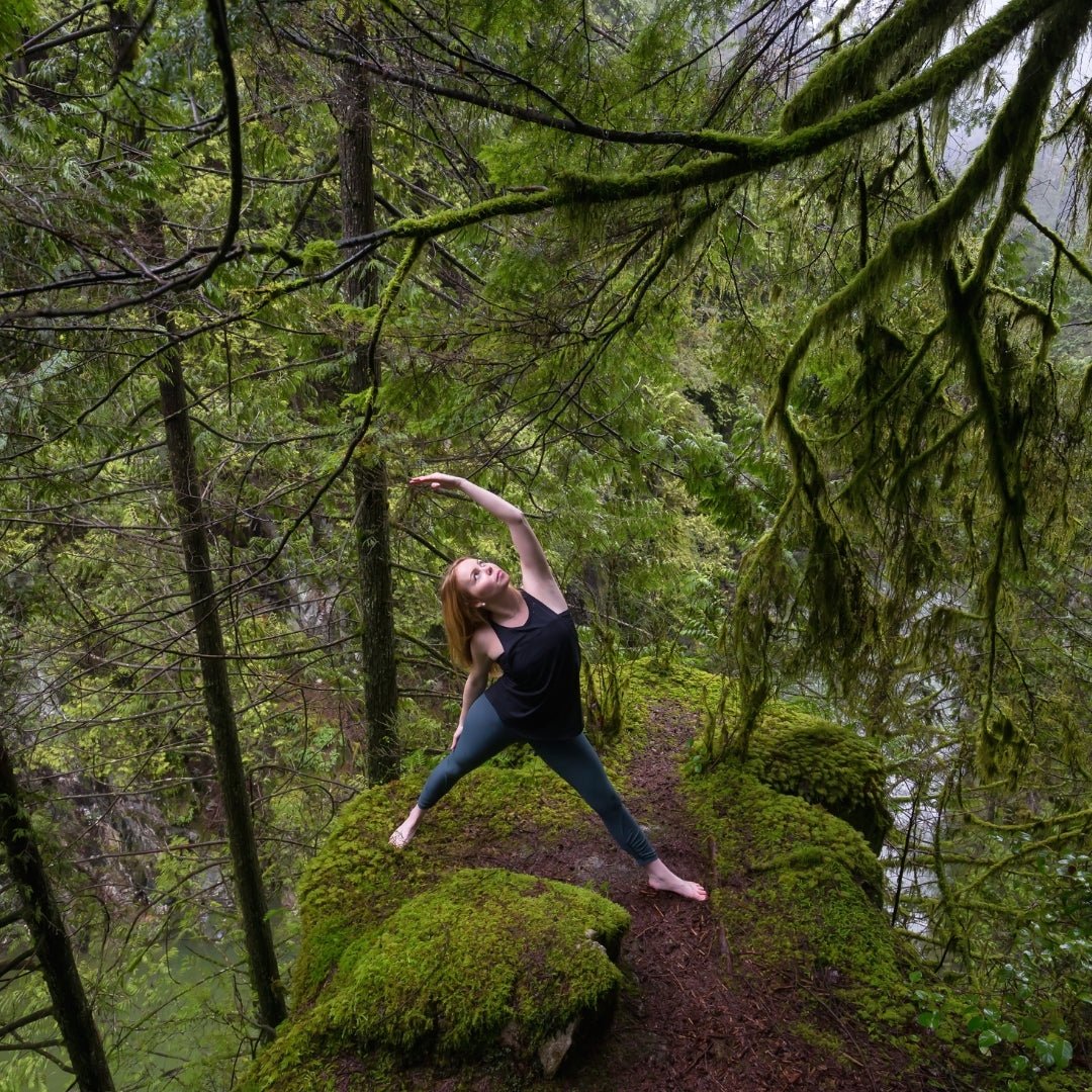 Woman practicing Nature Yoga & Mindfulness outdoors surrounded by lush green forest moss, Lapin Väki.