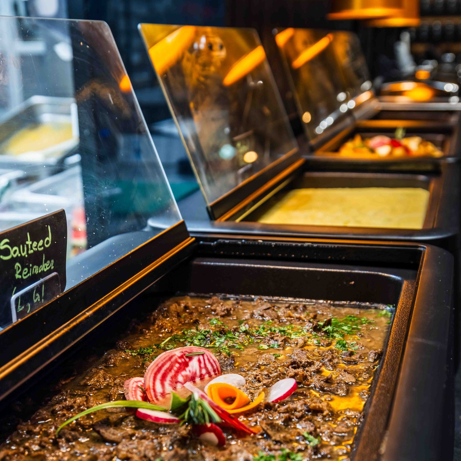 Buffet trays with sautéed reindeer and other dishes at Santa's Cuisine Restaurant by Santa Claus Holiday Village