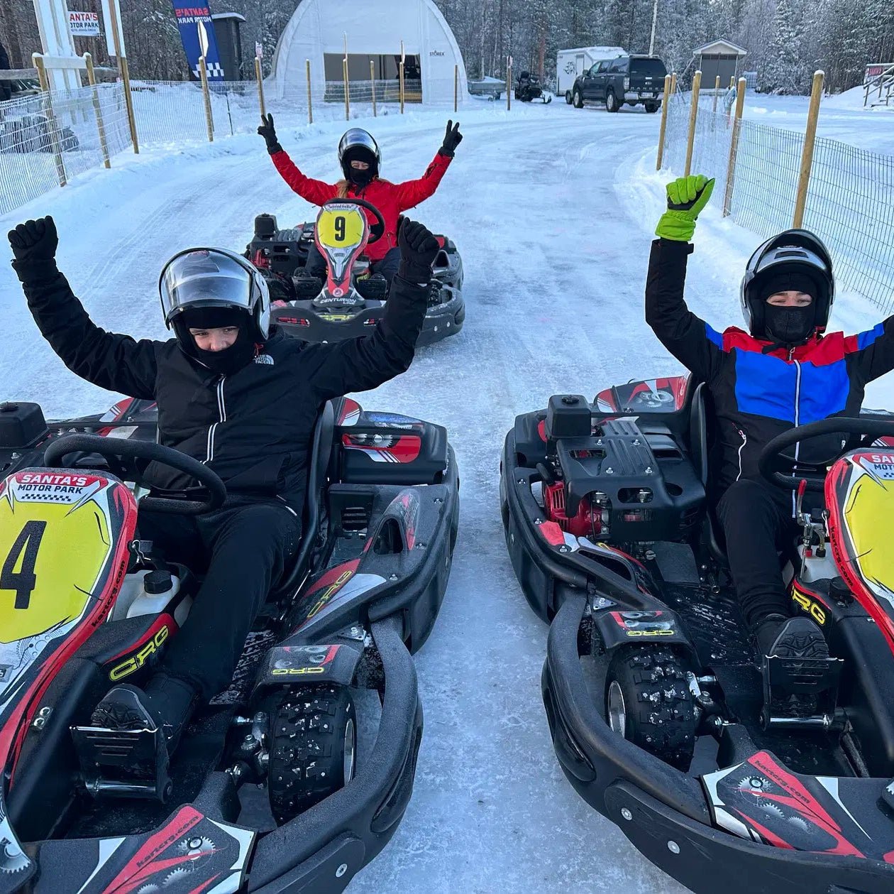 Three racers in helmets celebrating on snowy ice karts at Santa´s Ice Karting start 14.00 by Santa's motor park