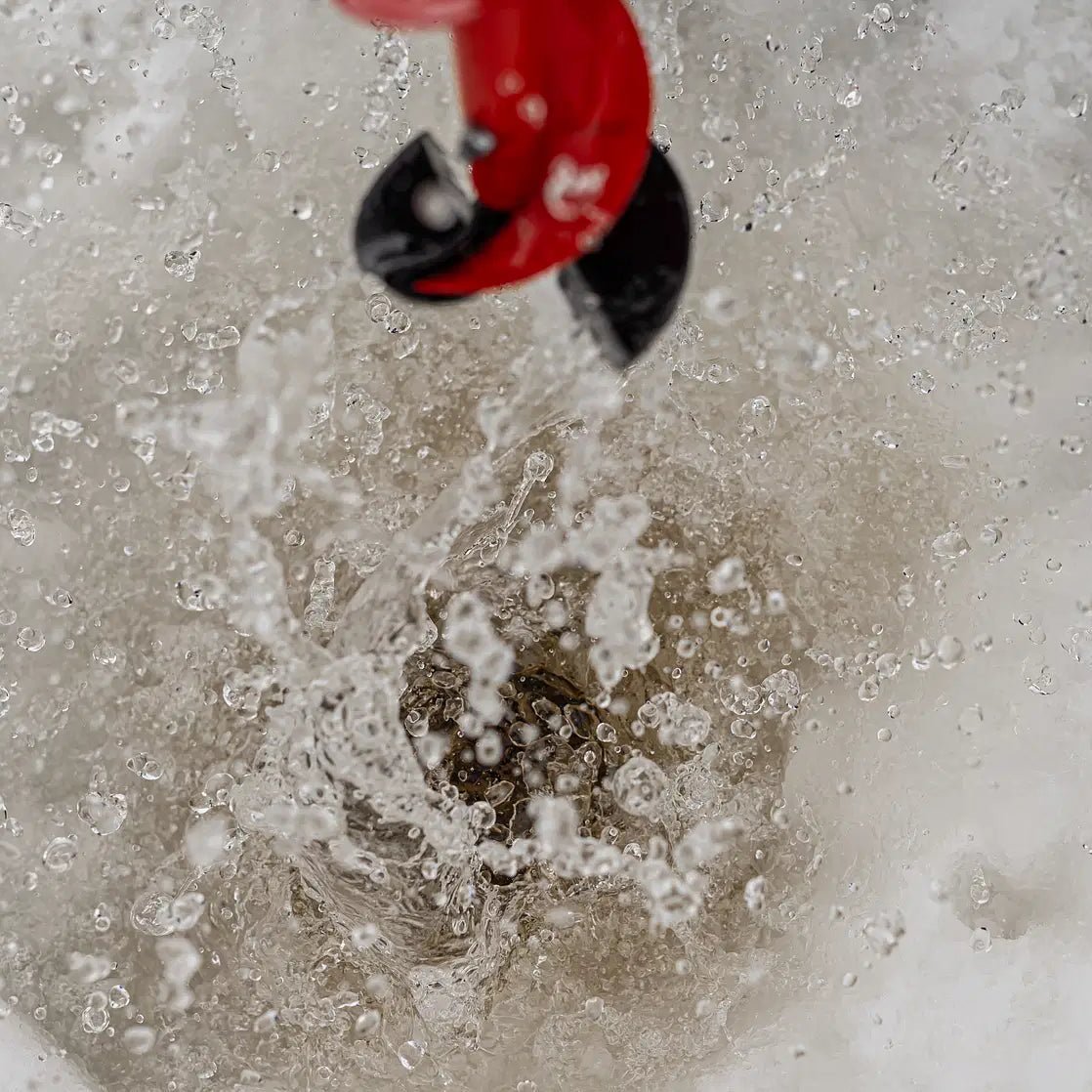 Ice fishing drill in action on frozen lake during Skiing and Fishing on Ice Adventure by Beyond Arctic