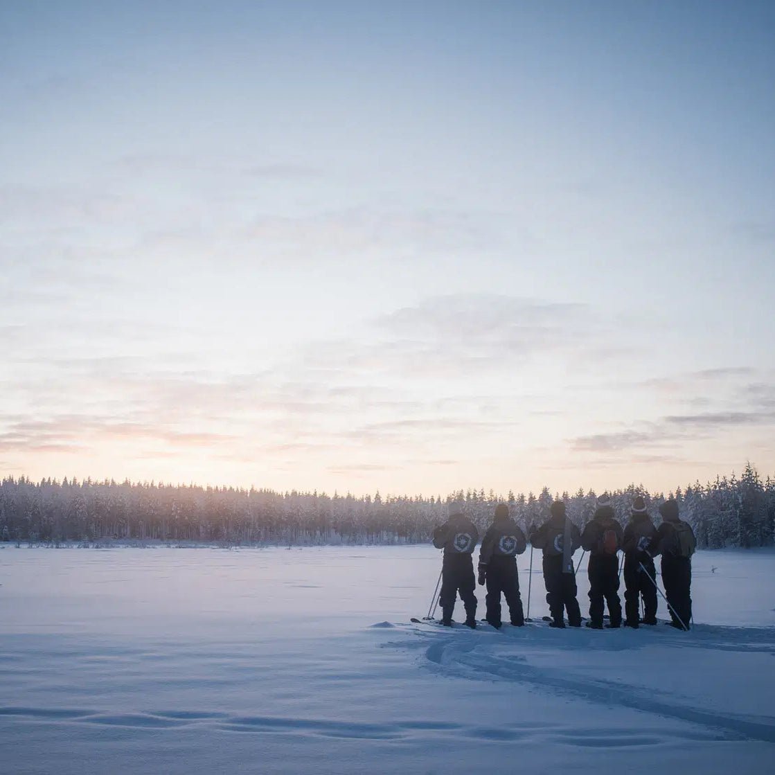 Group skiing on a frozen lake at sunset during Skiing and Fishing on Ice Adventure by Beyond Arctic