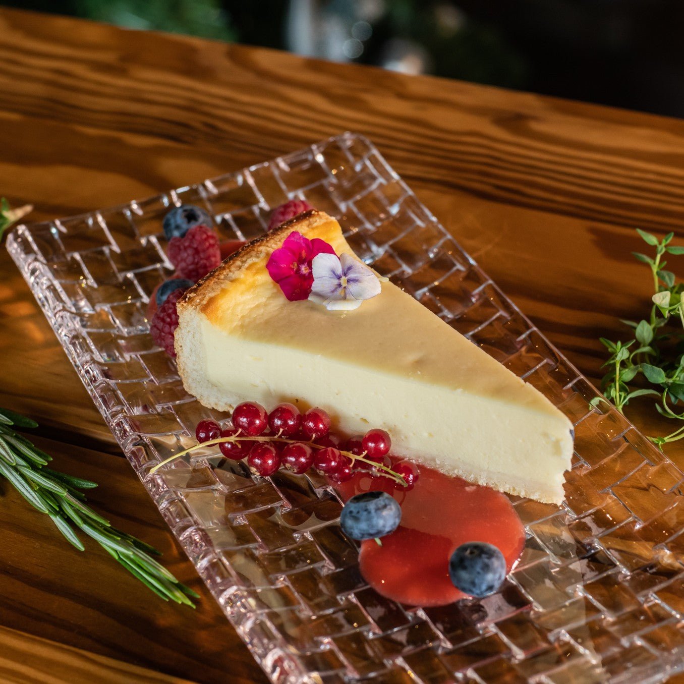 Slice of cheesecake with berries and edible flowers on a glass plate from Three Elves Restaurant Santa Claus Holiday Village